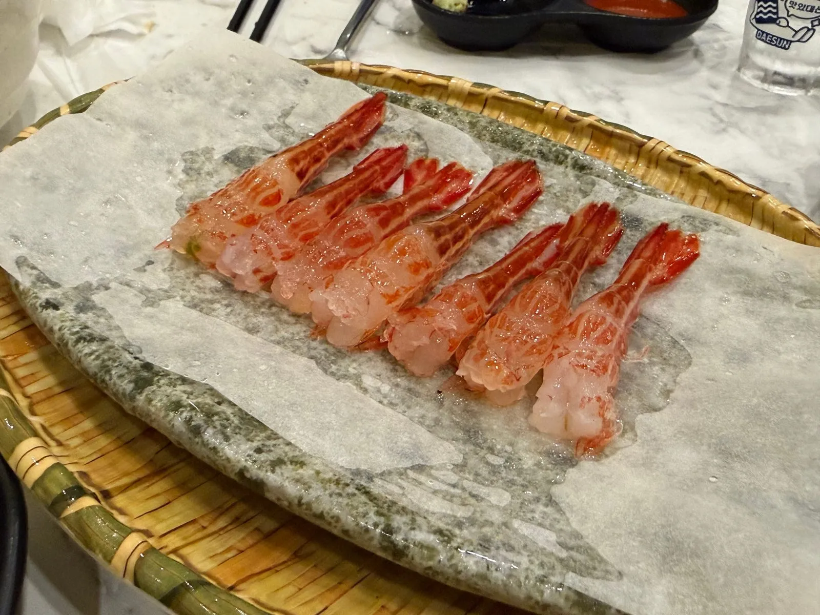 얼음을 깐 돌판 위에 껍질을 벗겨 나란히 놓은 꽃새우 회