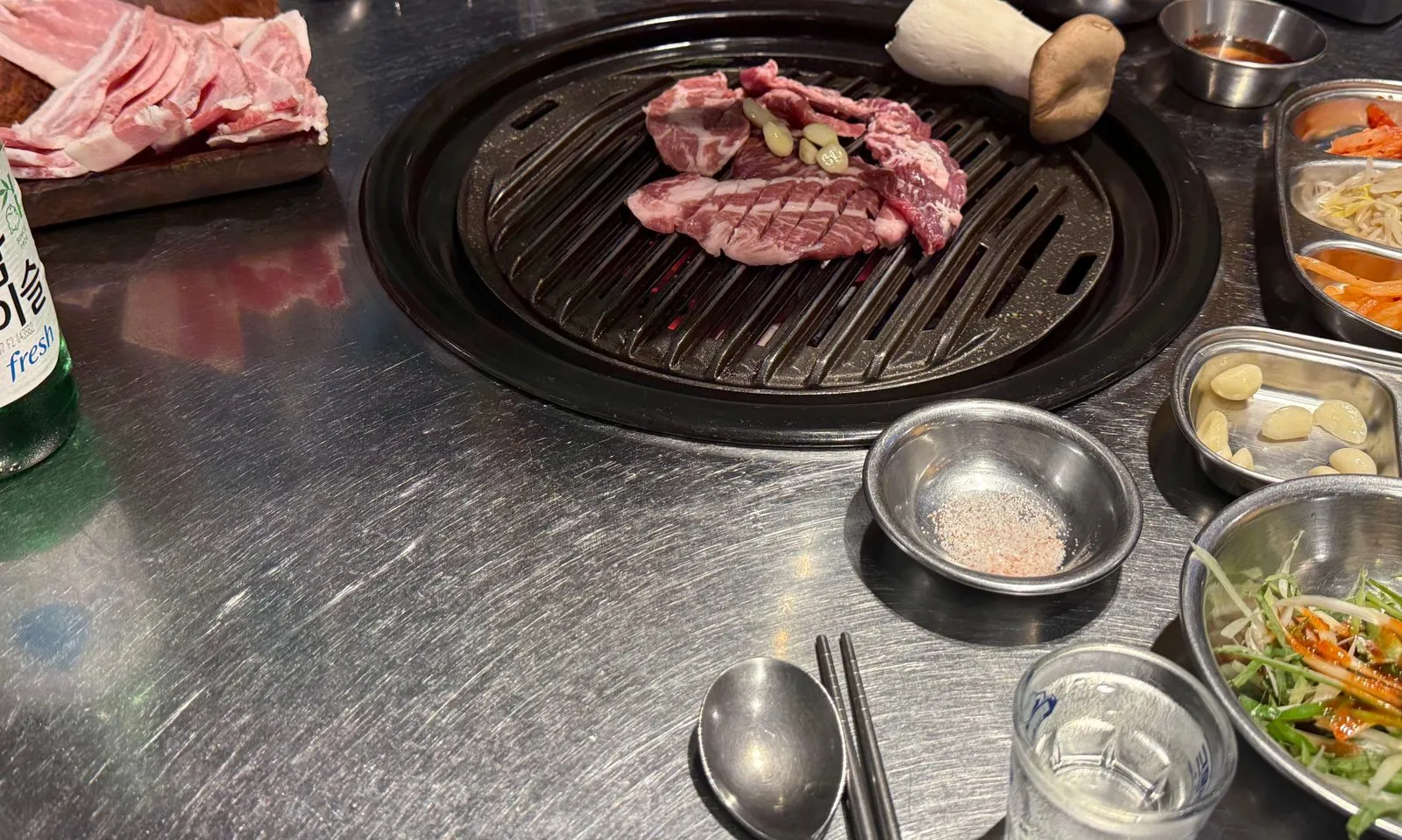 둥근 불판 위에서 익고 있는 고기와 둘레에 놓인 반찬 그릇들