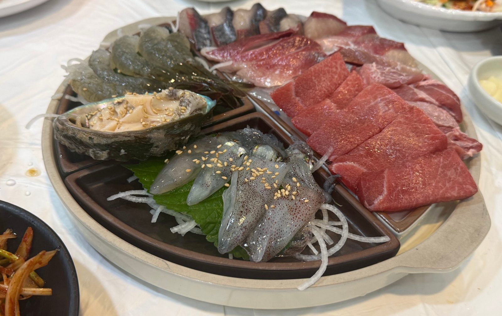 칸이 나뉜 접시에 붉은 참치와 새우, 전복 등을 담은 모둠