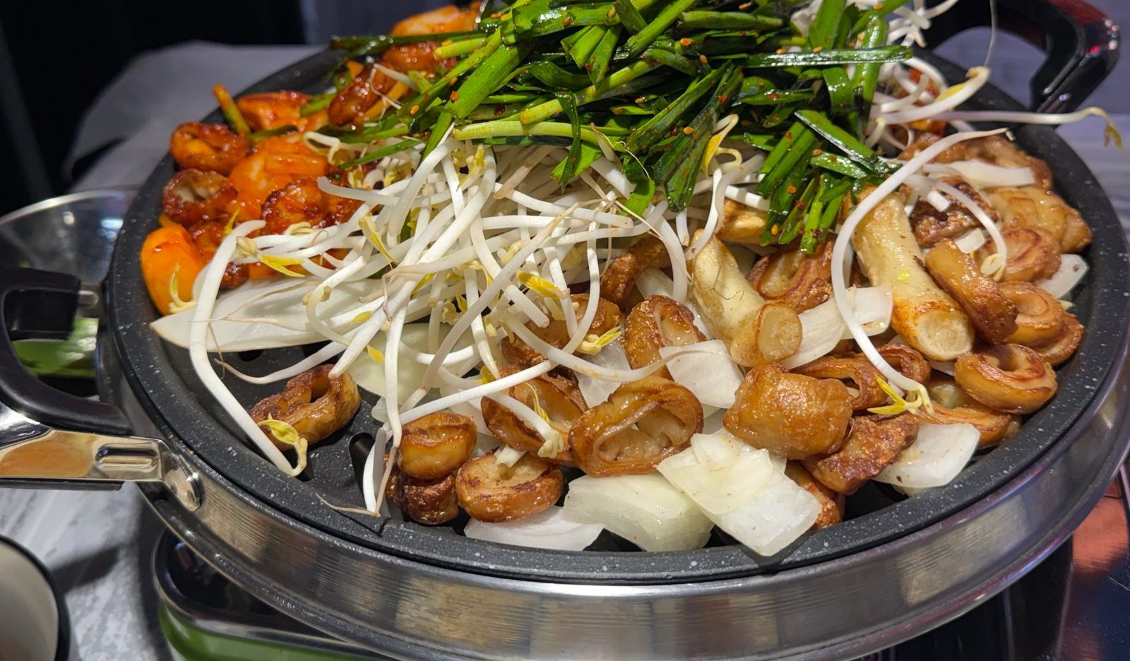 둥근 철판에 막창과 콩나물, 부추를 올려 굽는 모습