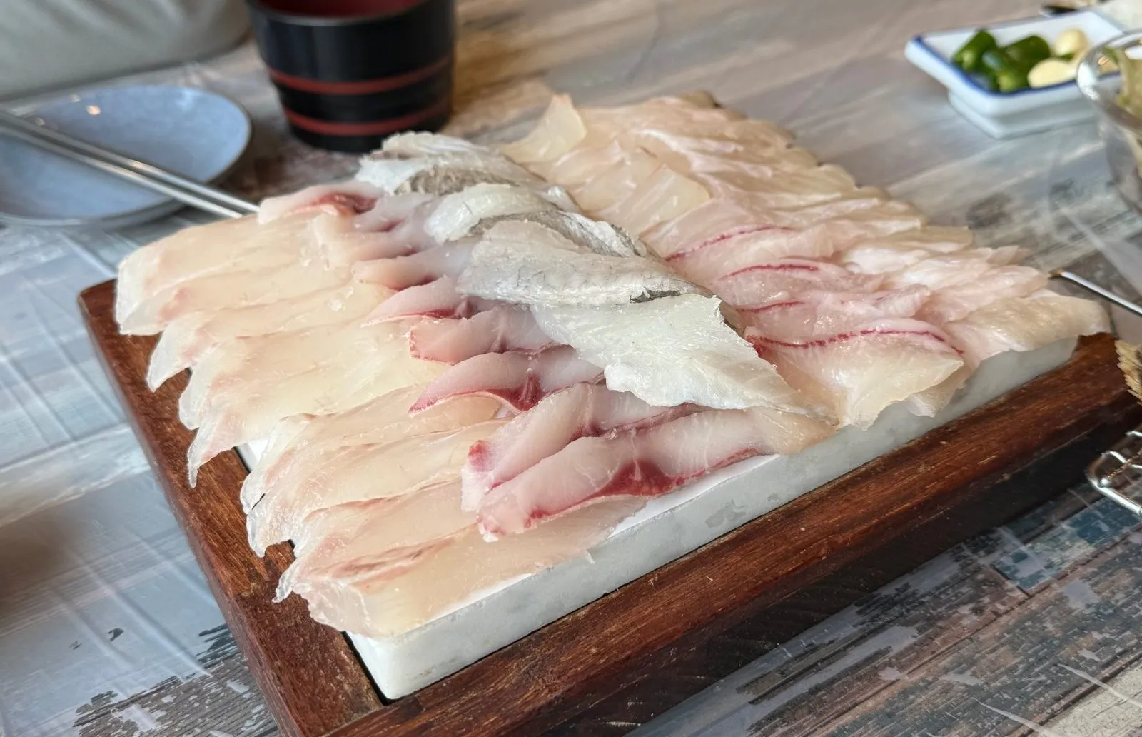 나무 도마 위에 가지런히 놓인 도톰한 흰살 생선회