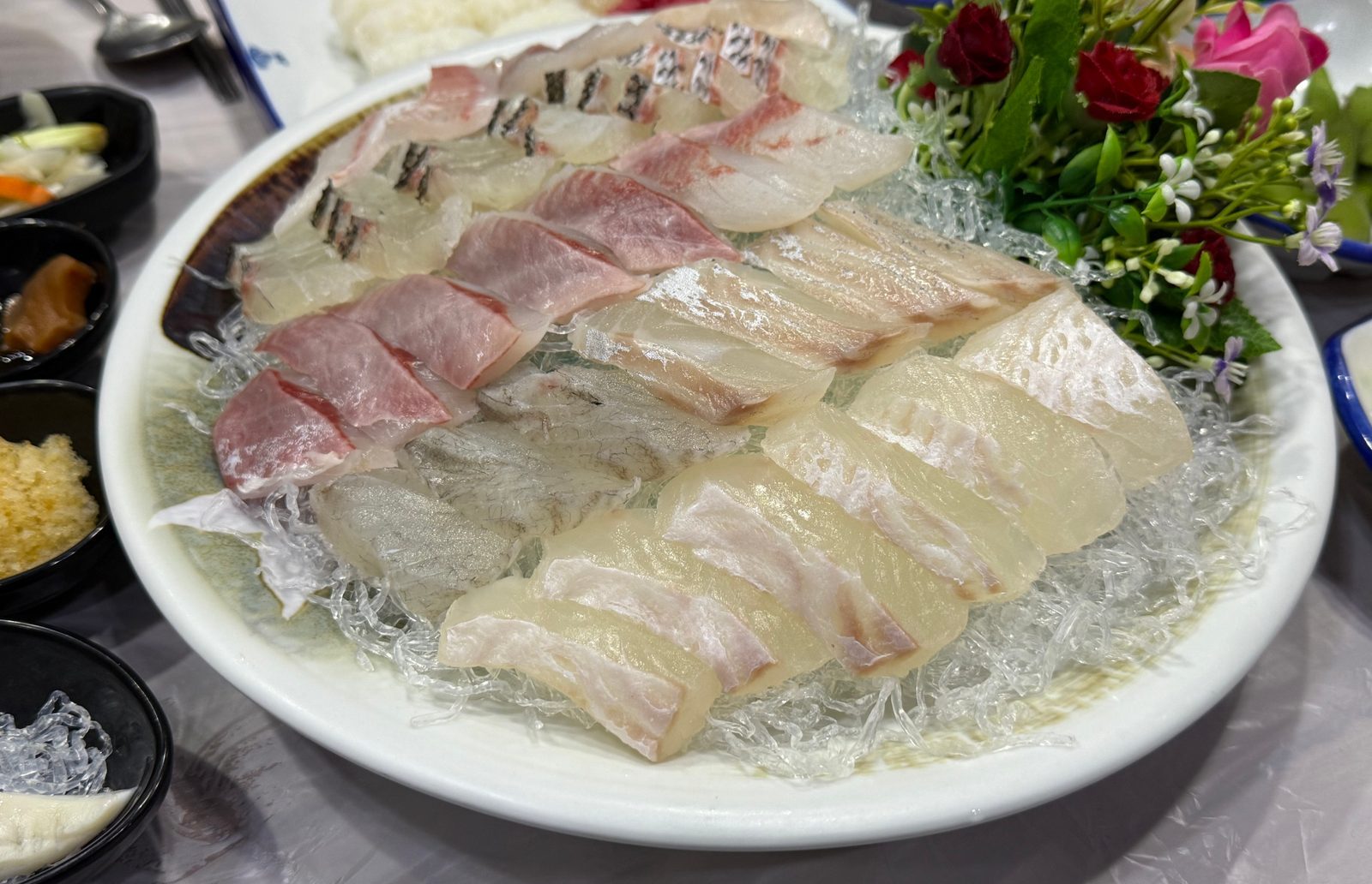 꽃 장식을 곁들인 큰 접시에 여러 생선의 회를 담은 모둠회