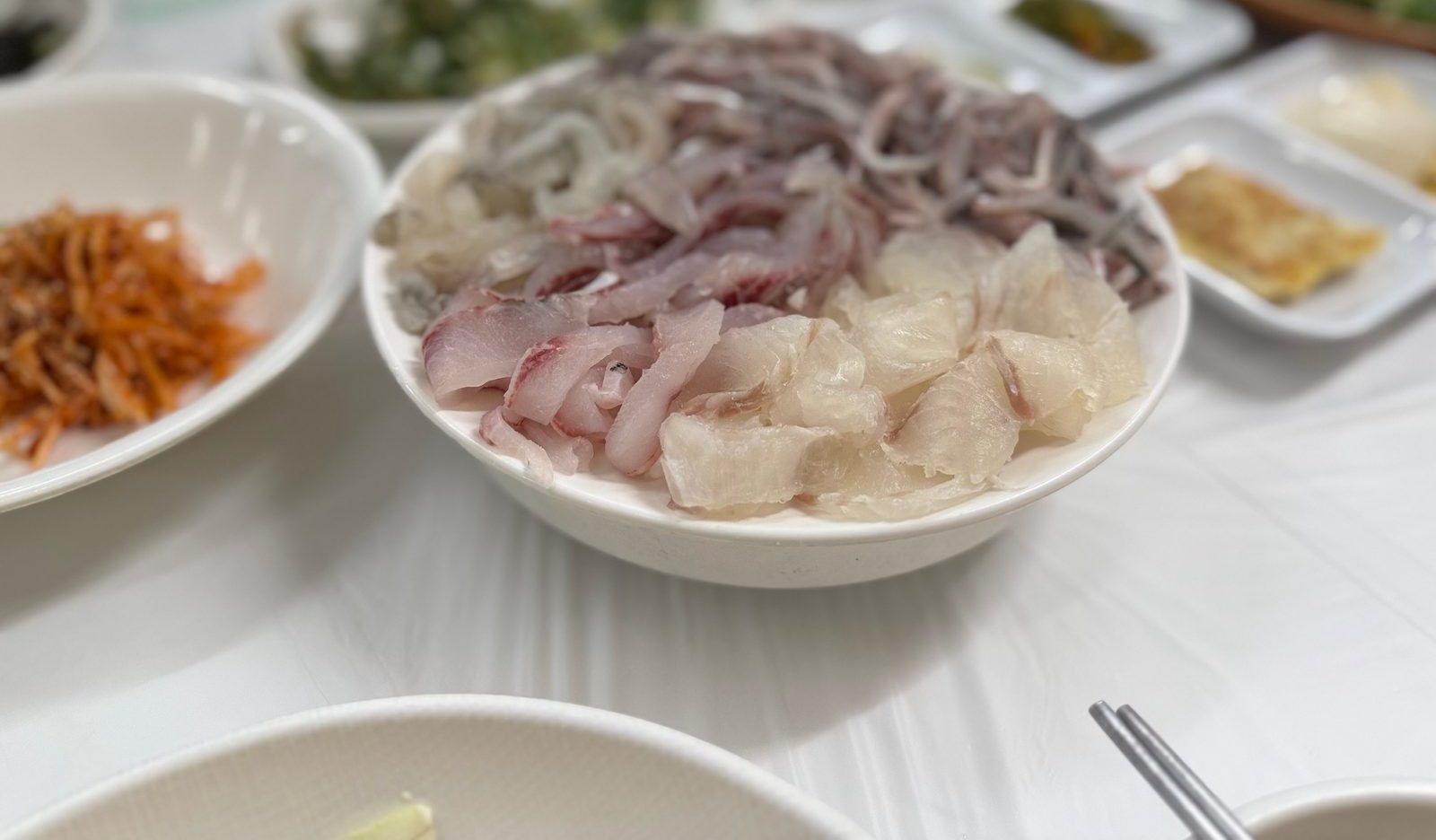 흰 그릇에 수북이 담긴 모듬회와 전어회