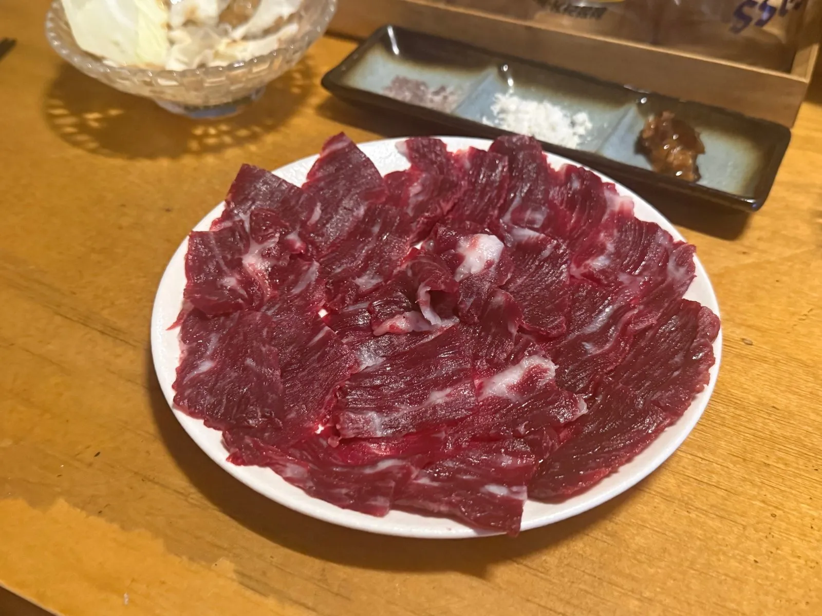 흰 접시에 얇게 썰어 펼쳐 담은 붉은 생고기