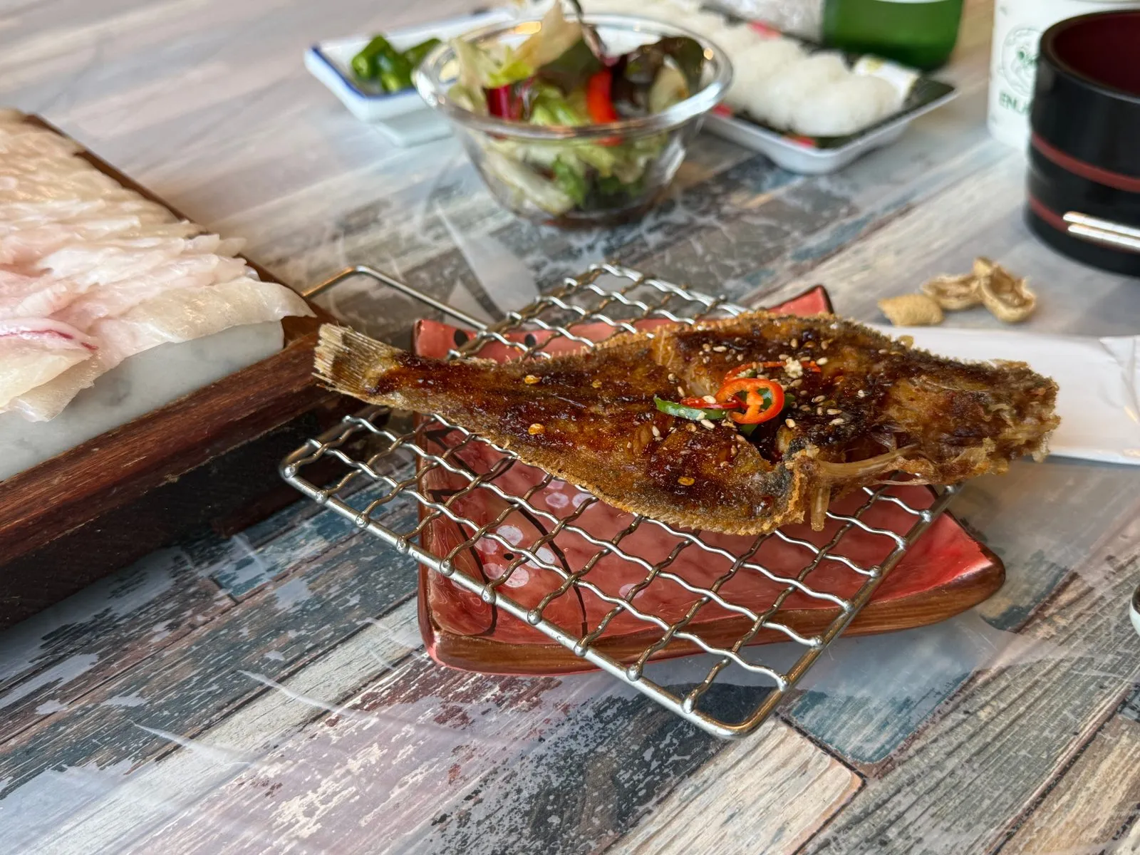 석쇠 받침 위에 놓인 양념을 얹은 가자미구이