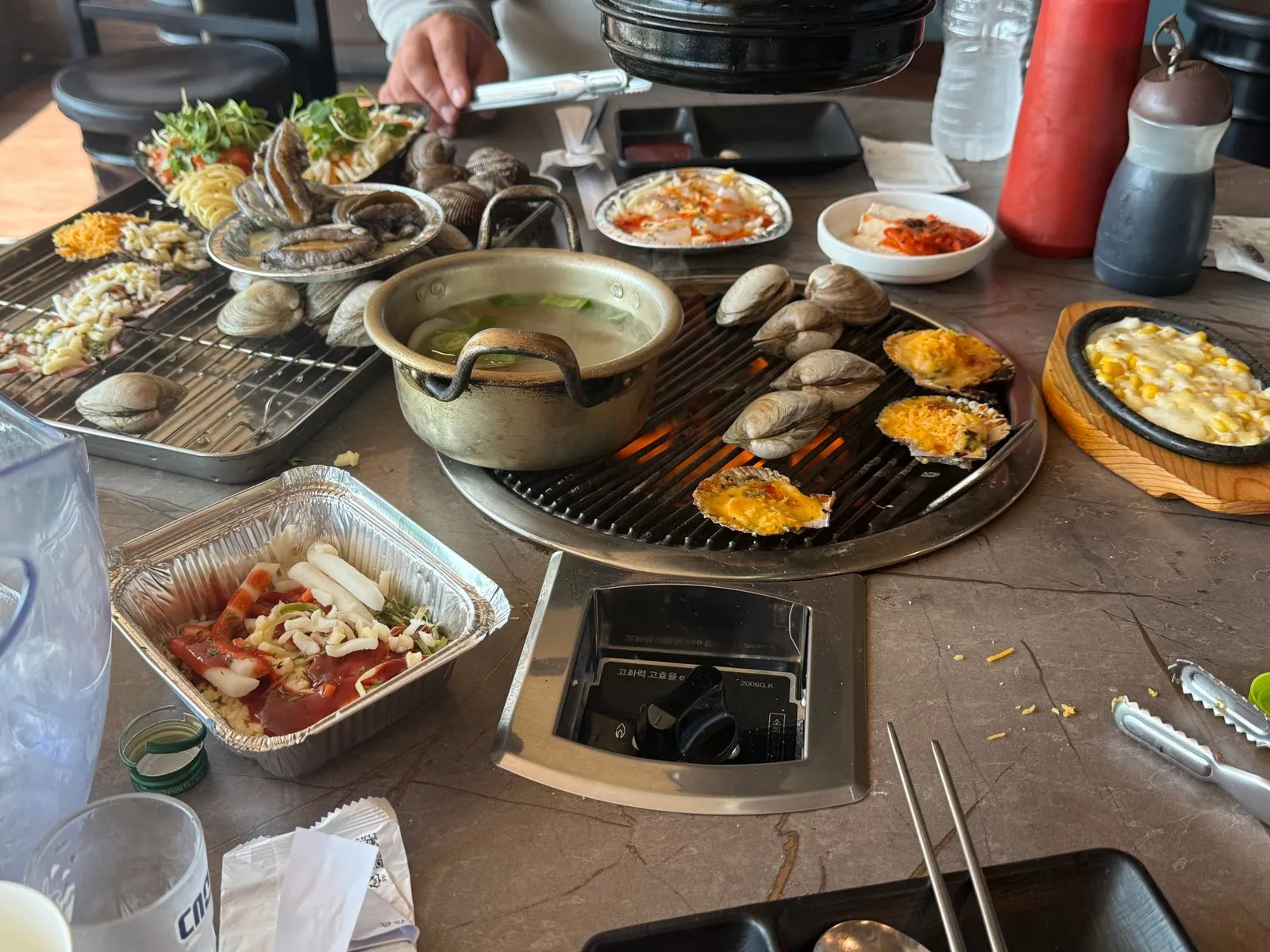 불판 두 곳에 조개와 가리비, 치즈 요리가 올라가 있는 상차림