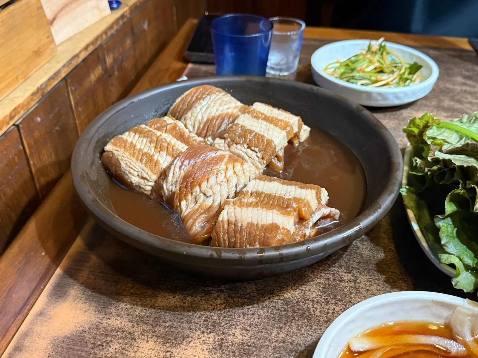 양념에 잠긴 갈비가 담긴 넓은 그릇과 쌈 채소