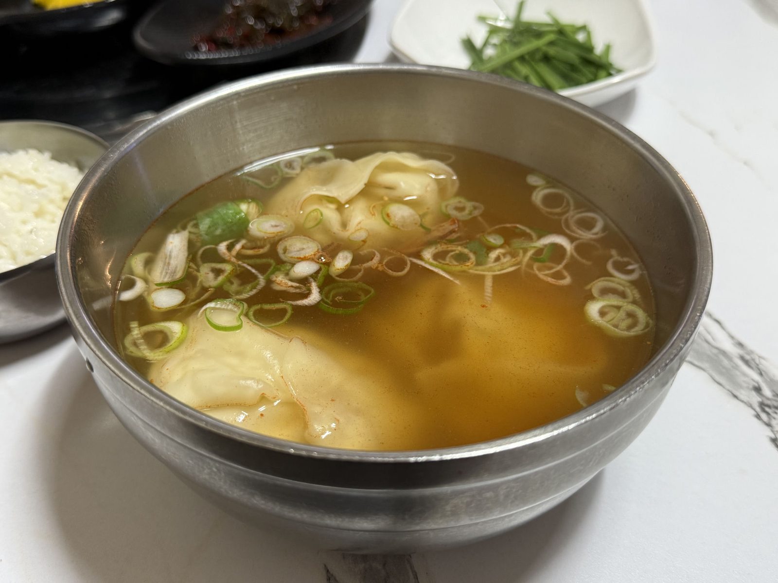 맑은 국물에 큼직한 만두와 송송 썬 파가 담긴 만둣국 한 그릇