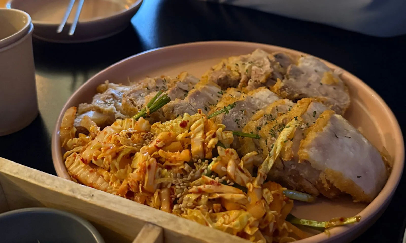 넓은 접시에 양념에 무친 채소와 함께 담긴, 썰어 놓은 수육카츠