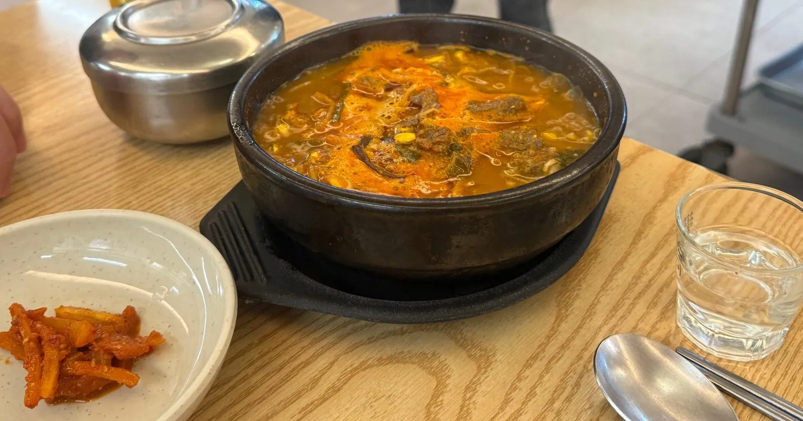 뚝배기에 담긴 붉은 국물의 한우국밥과 깍두기
