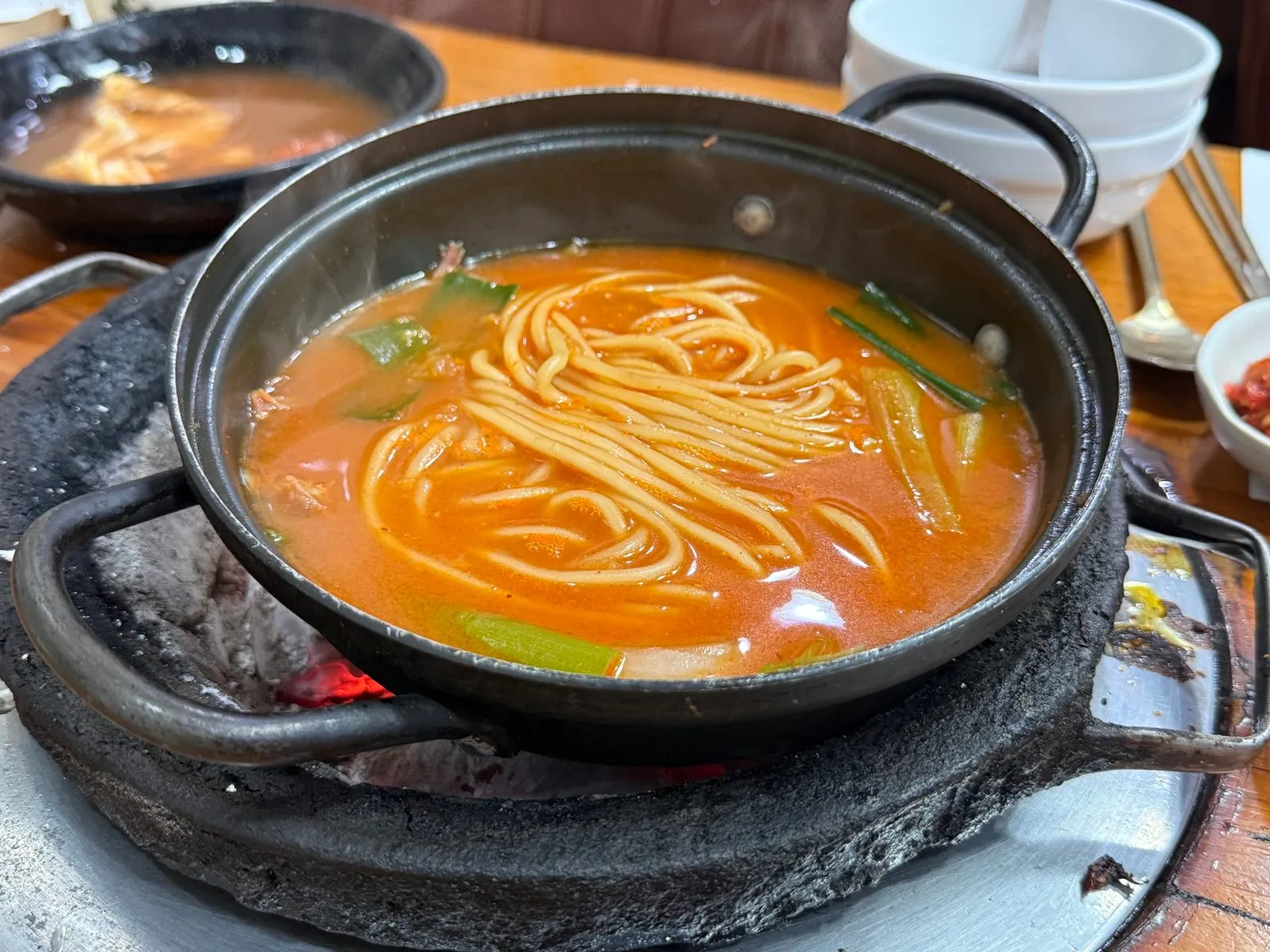 검은 냄비에 담긴 붉은 국물의 우동
