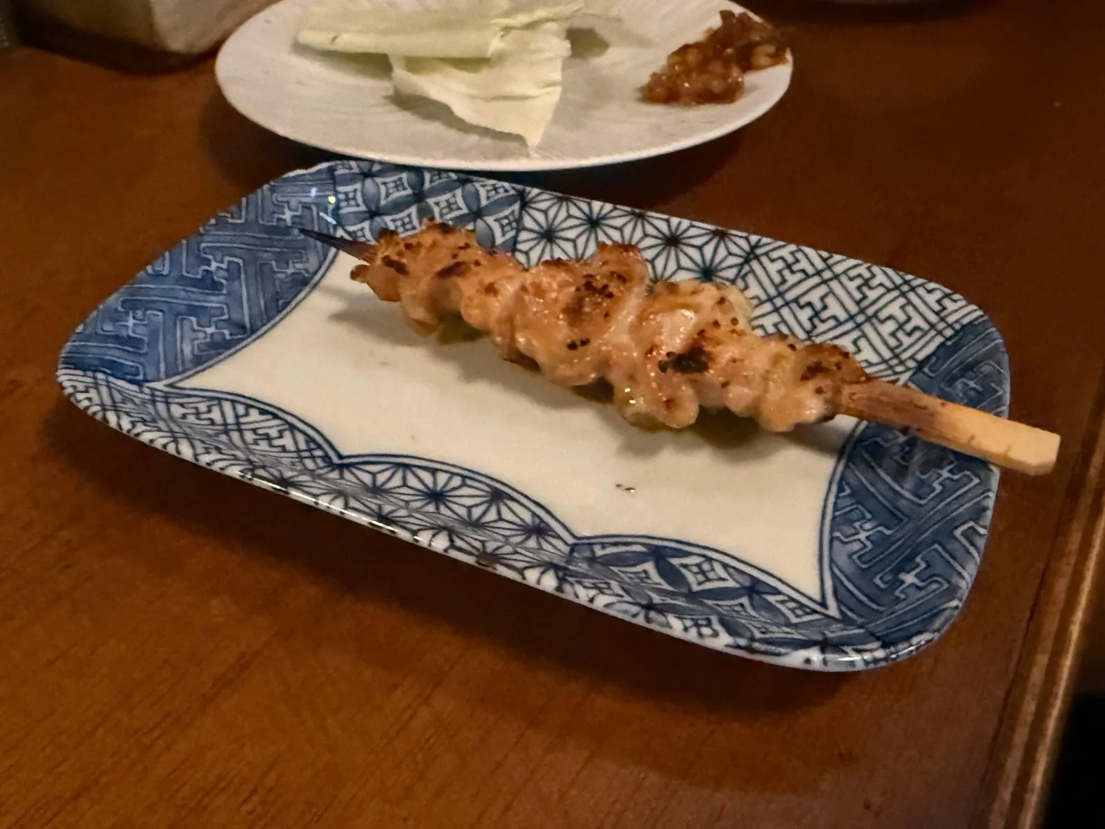 푸른 무늬 접시에 놓인 닭 껍질 꼬치 하나