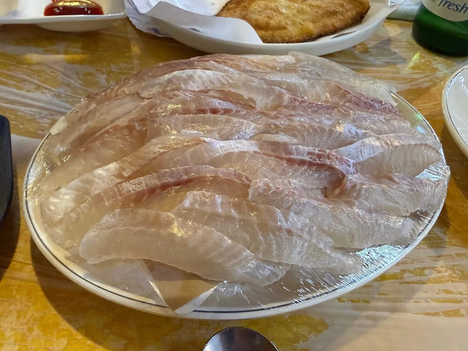 넓은 접시에 얇게 떠서 가지런히 놓은 흰살 생선회