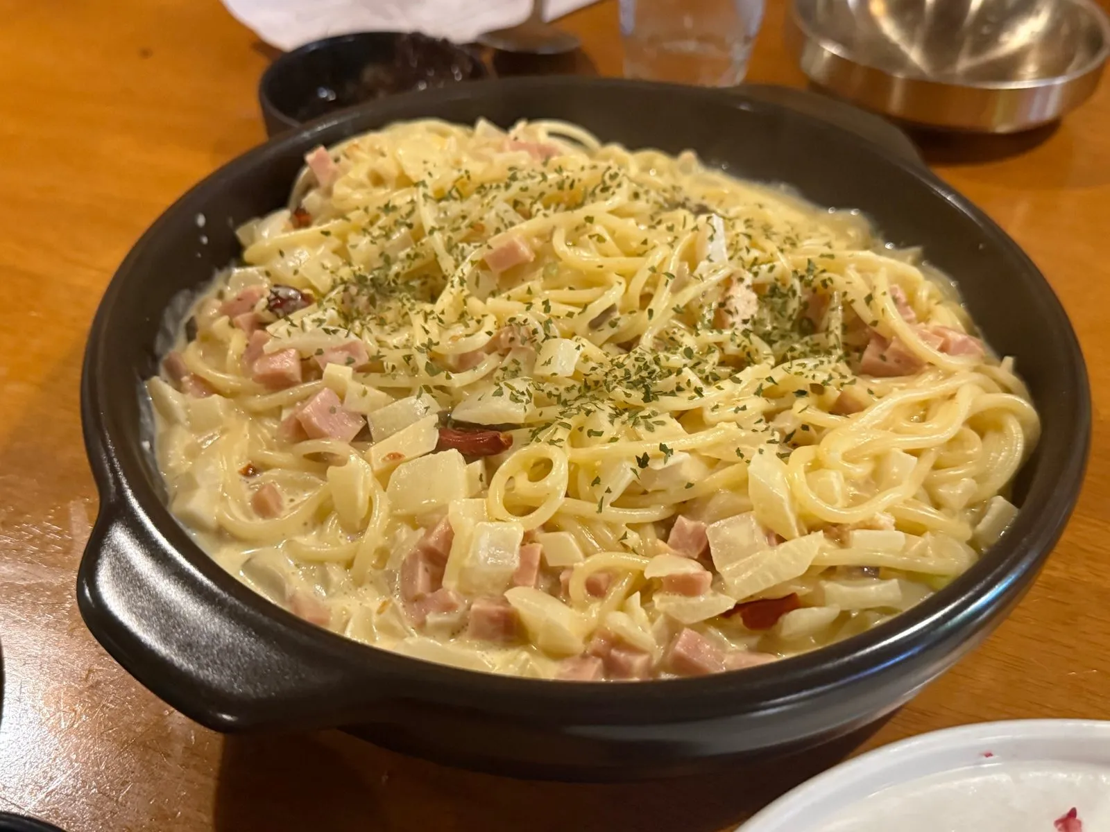검은 그릇에 담긴 크림 파스타와 그 위에 뿌린 파슬리